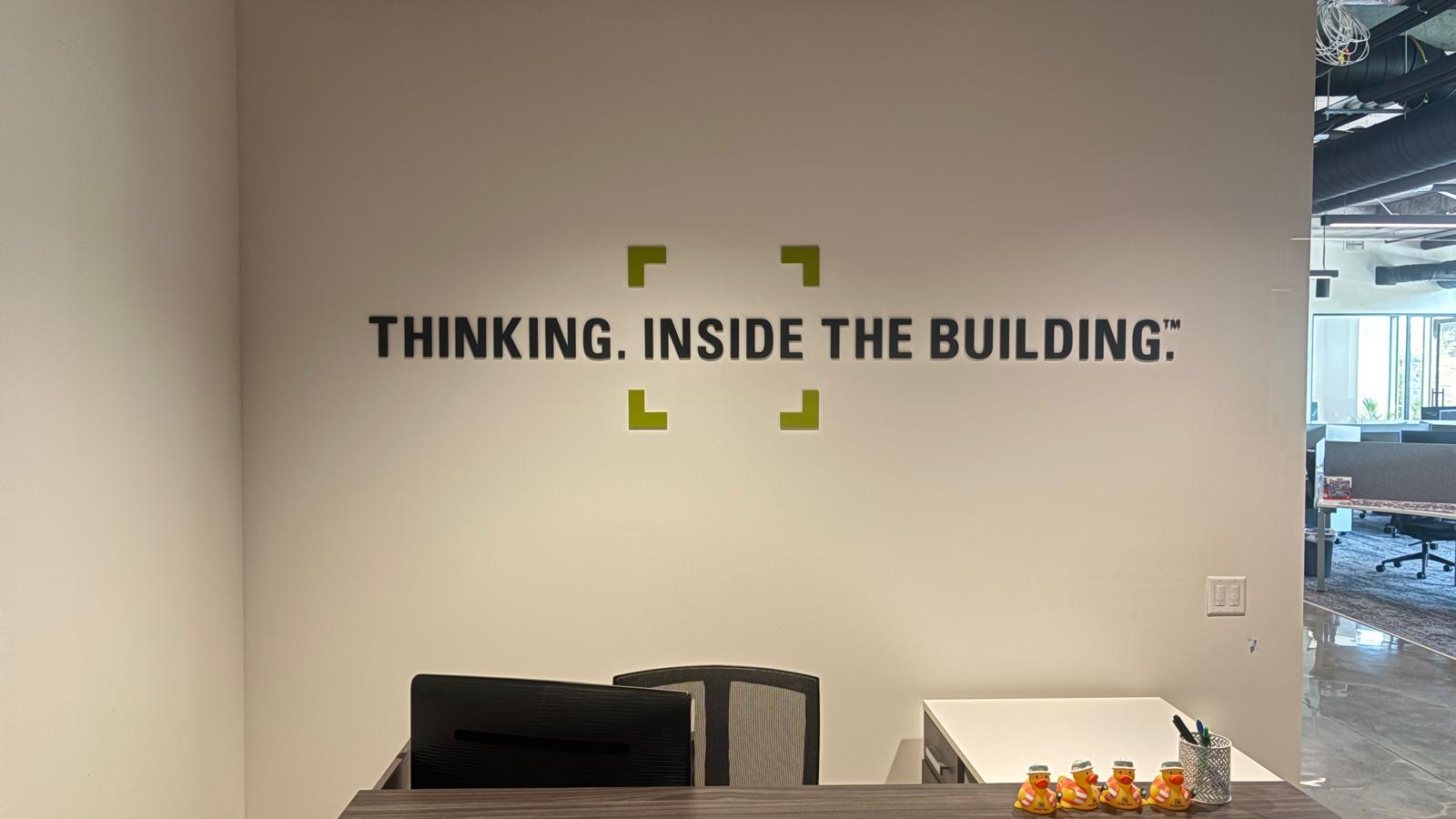 Dimensional wall lettering reading 'Thinking Inside the Building' installed in a corporate reception area