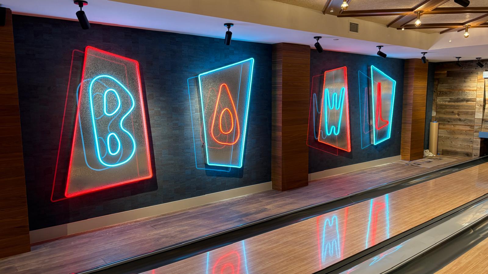 Large red and blue neon channel letters spelling BOWL along a bowling lane wall