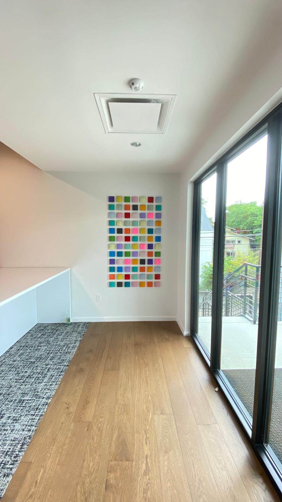 Grid of small colorful glass tiles mounted on a residential wall